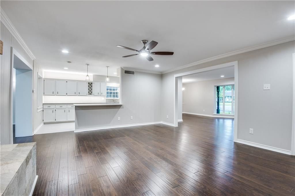 An empty living room with hardwood floors and a ceiling fan.