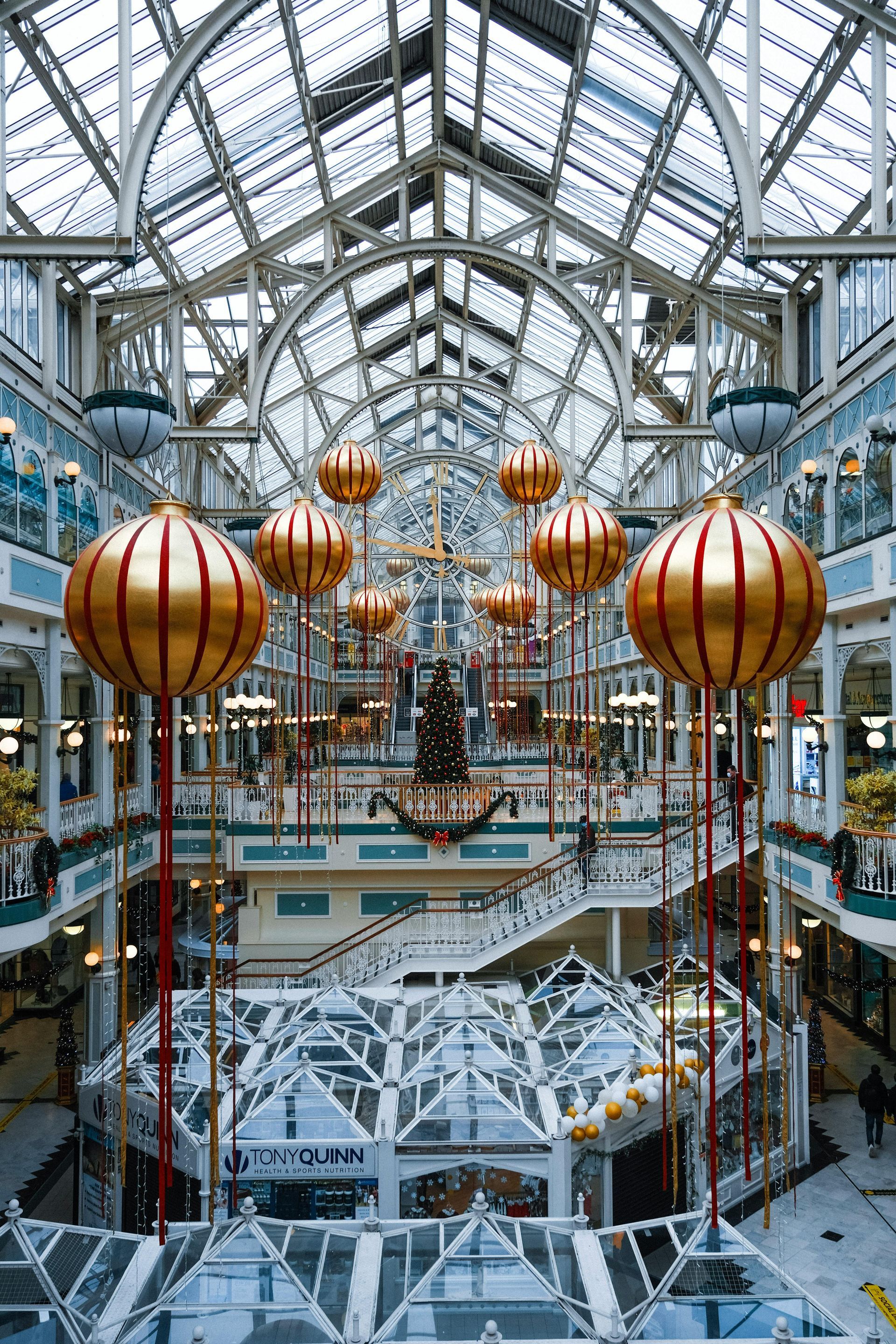 A large shopping mall decorated for christmas with balloons and a christmas tree.