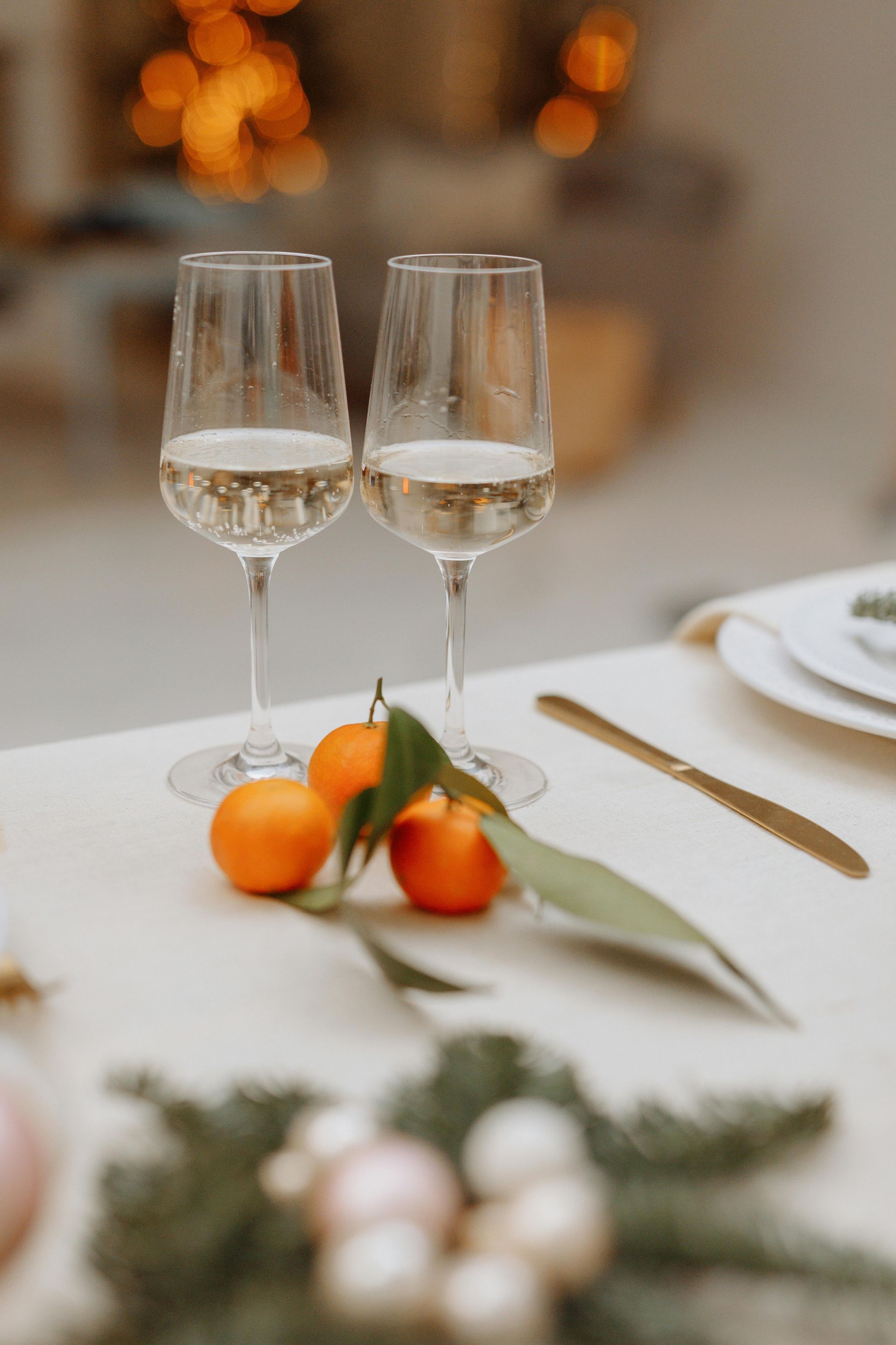 Two glasses of champagne and oranges on a table.