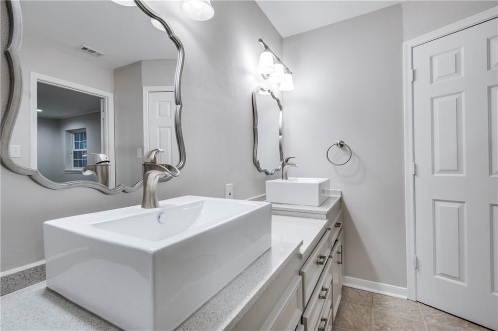 A bathroom with a sink , mirror , and cabinets.
