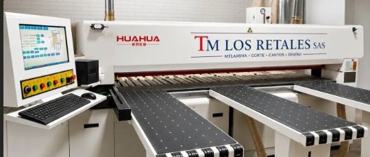 Gran máquina CNC industrial en un taller con señalización en español para proyectos personalizados y expositores comerciales.
