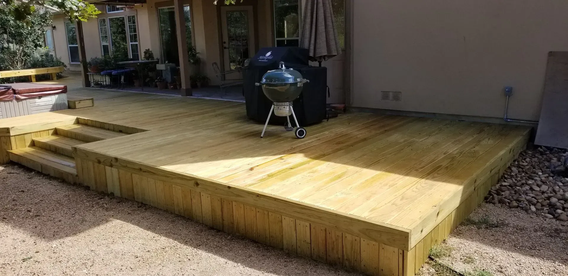 Wooden deck with steps, a grill, and a home exterior.