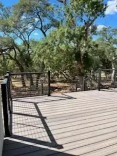 Wooden deck with black metal railing overlooking trees.