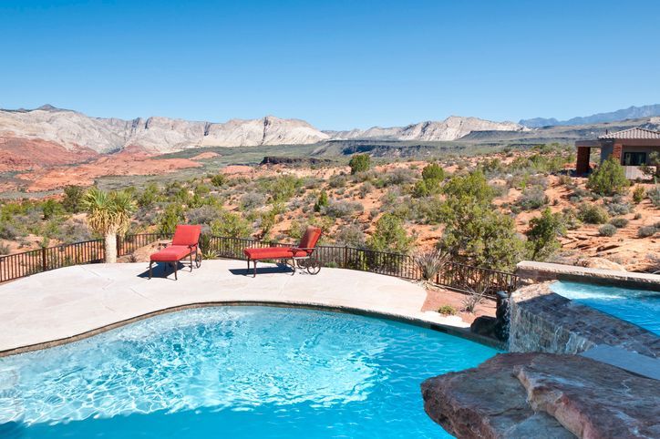Backyard pool with red lounge chairs and desert mountains in the distance