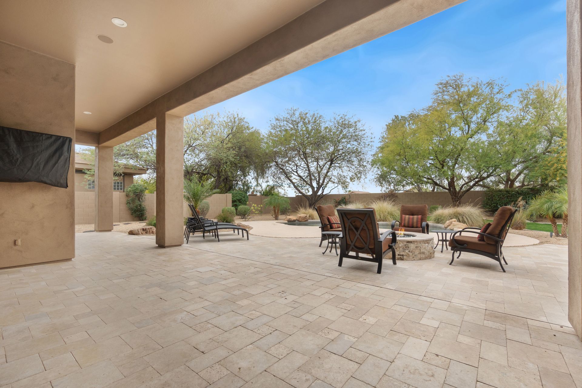A cozy patio featuring several chairs arranged around a central fireplace.