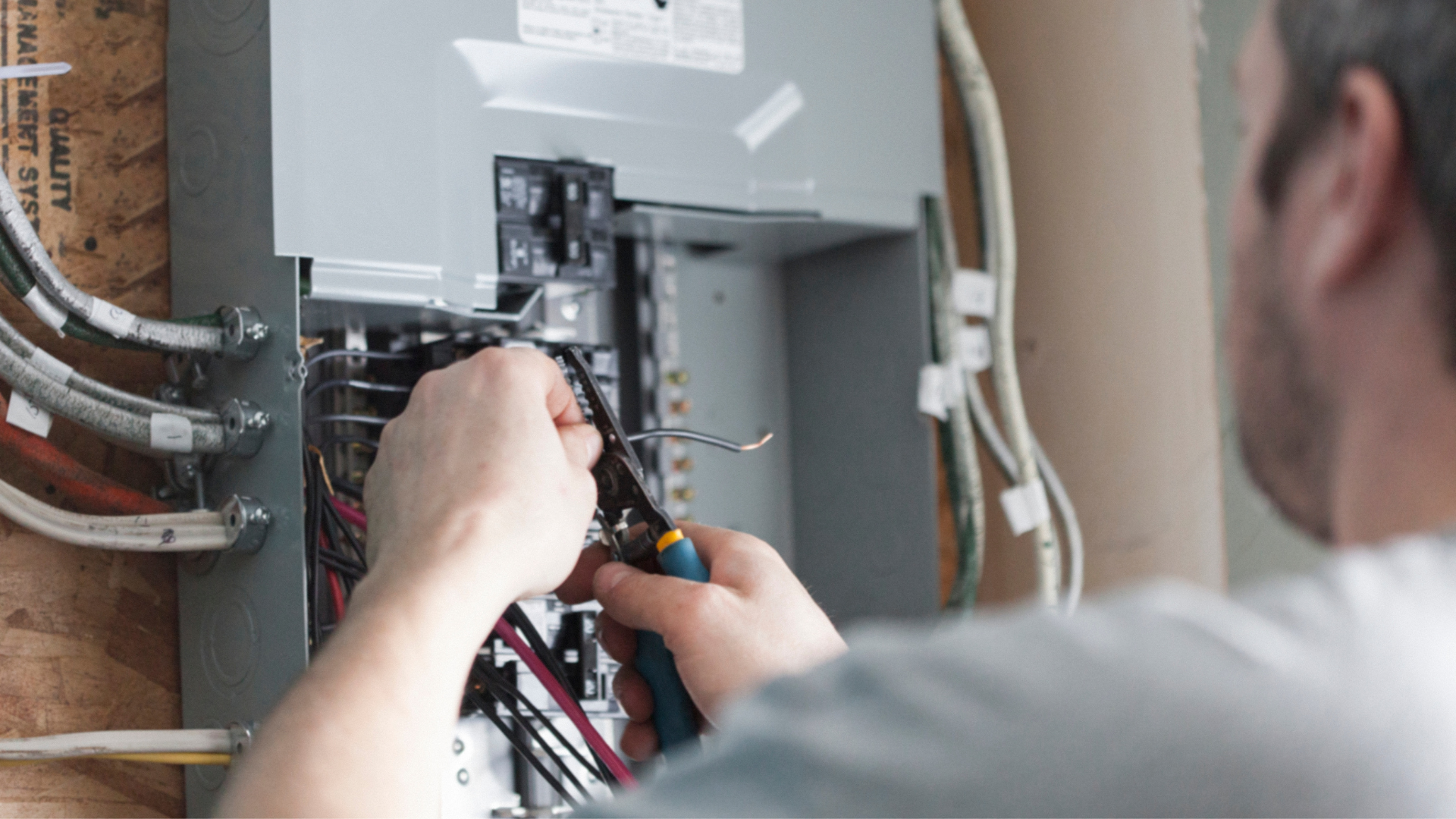 A man is working on an electrical box with a screwdriver.