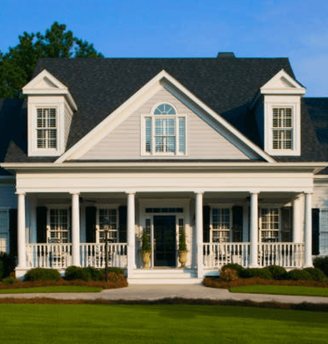 Large white house with black roof, front porch columns, and manicured green lawn