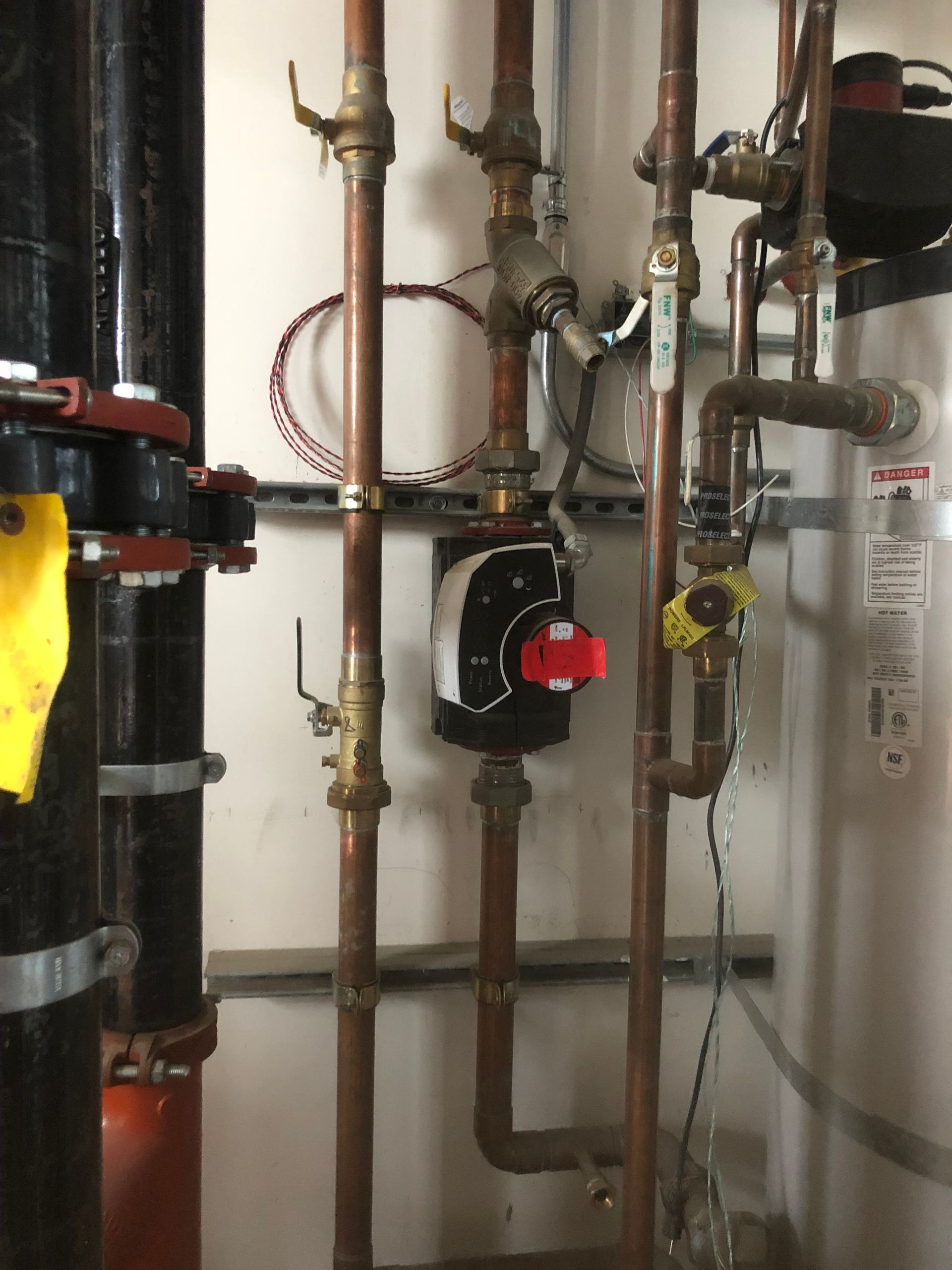 A room with a lot of copper pipes and a water heater