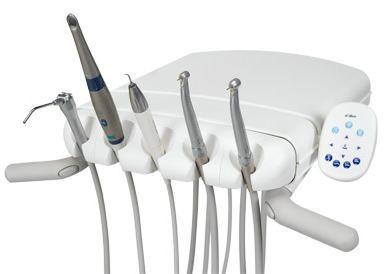 Dental tools: handpieces, air/water syringe, and control panel on a white dental unit.