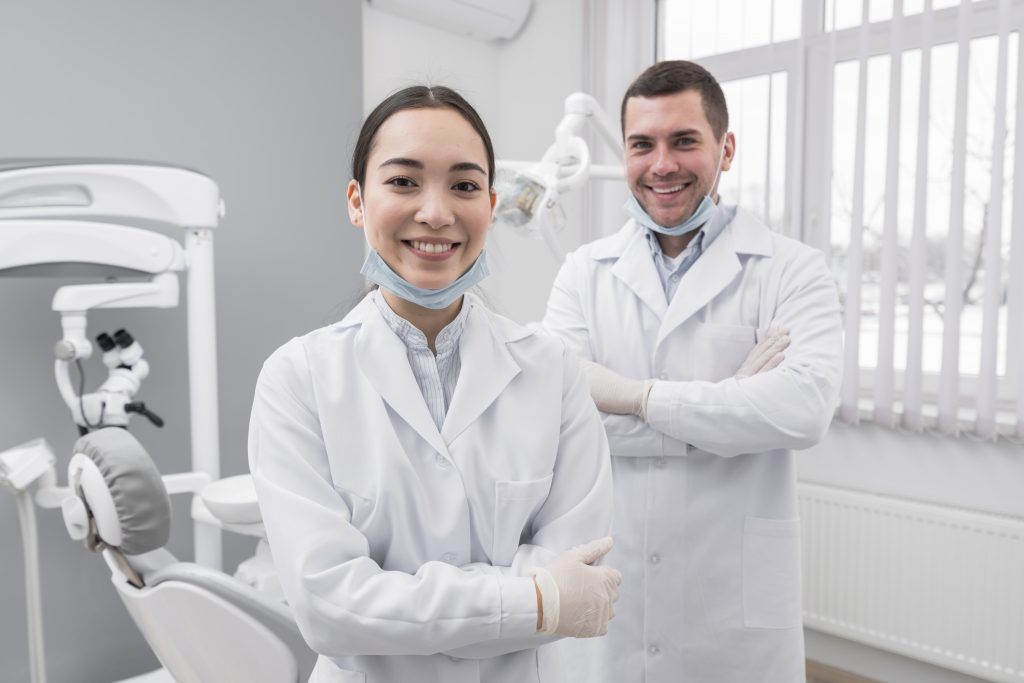 Two smiling dentists in lab coats in a dental office.