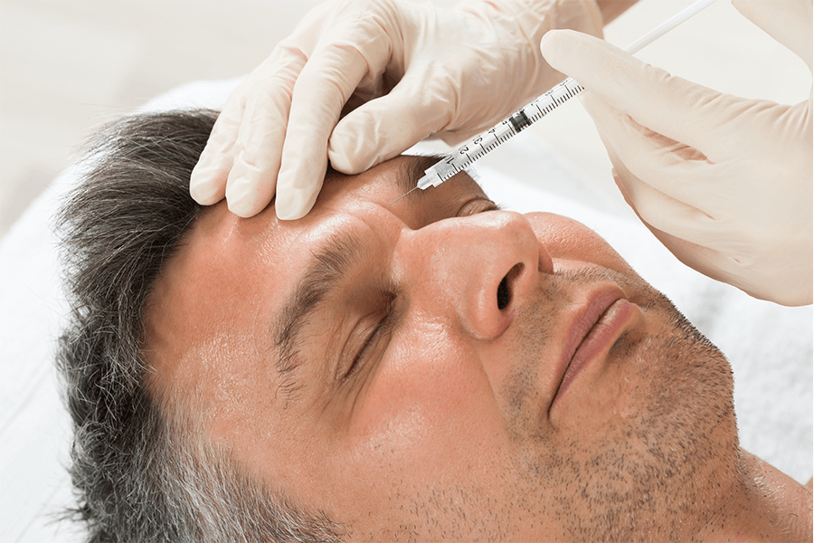A man is getting a botox injection in his forehead