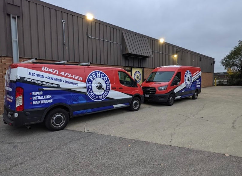 Two red, white, and blue Penco Electric & Generator vans parked in a concrete lot in front of a commercial building.