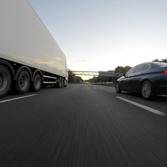 A white truck and a black car are driving down a highway