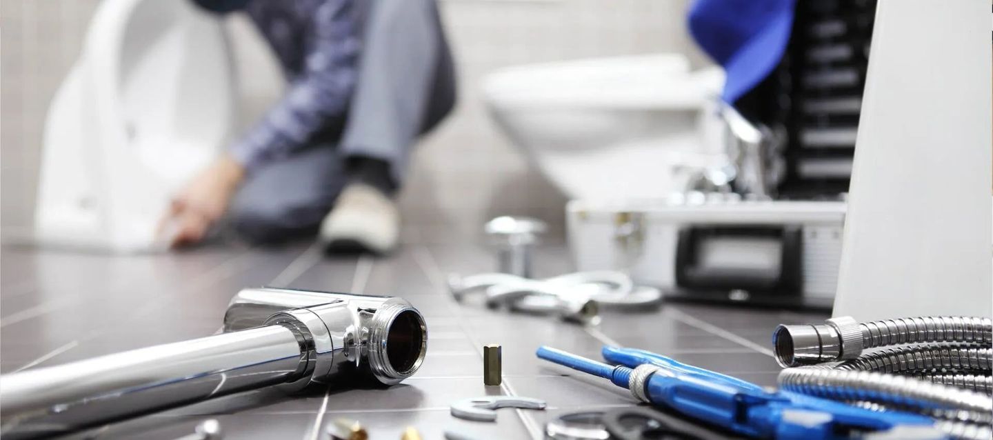 A Plumber Is Working On A Toilet In A Bathroom — Ashley Chick Plumbing In Baranduda, VIC