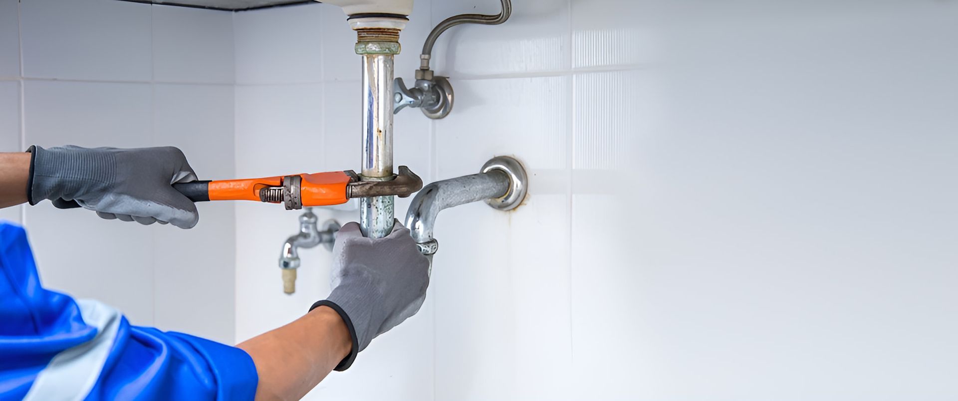 A Plumber Is Fixing A Sink Pipe With A Wrench — Ashley Chick Plumbing In Mitta Mitta, VIC