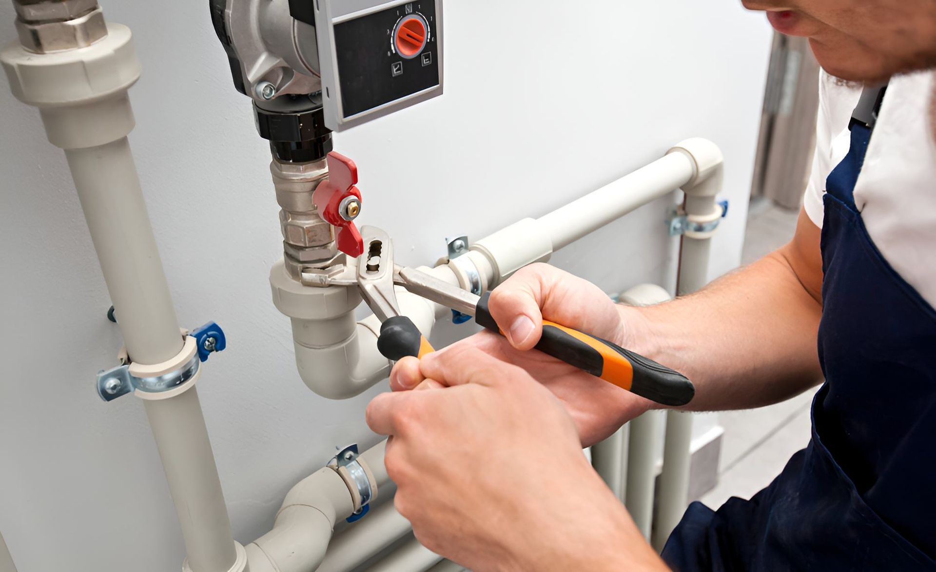 A Man Is Working On A Pipe With A Pair Of Pliers — Ashley Chick Plumbing In Baranduda, VIC