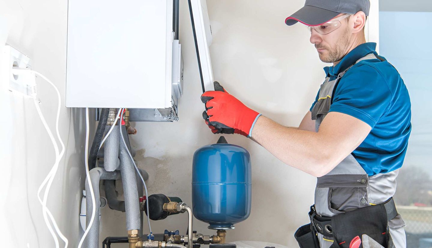 A Man Is Installing A Water Heater In A House — Ashley Chick Plumbing In Baranduda, VIC