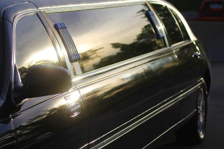 A black limousine is parked in a parking lot at sunset.