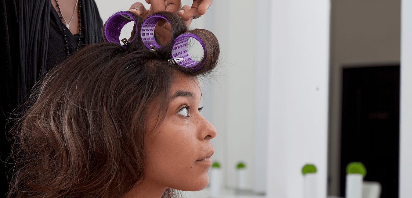 A woman is getting her hair curled by a hairdresser.