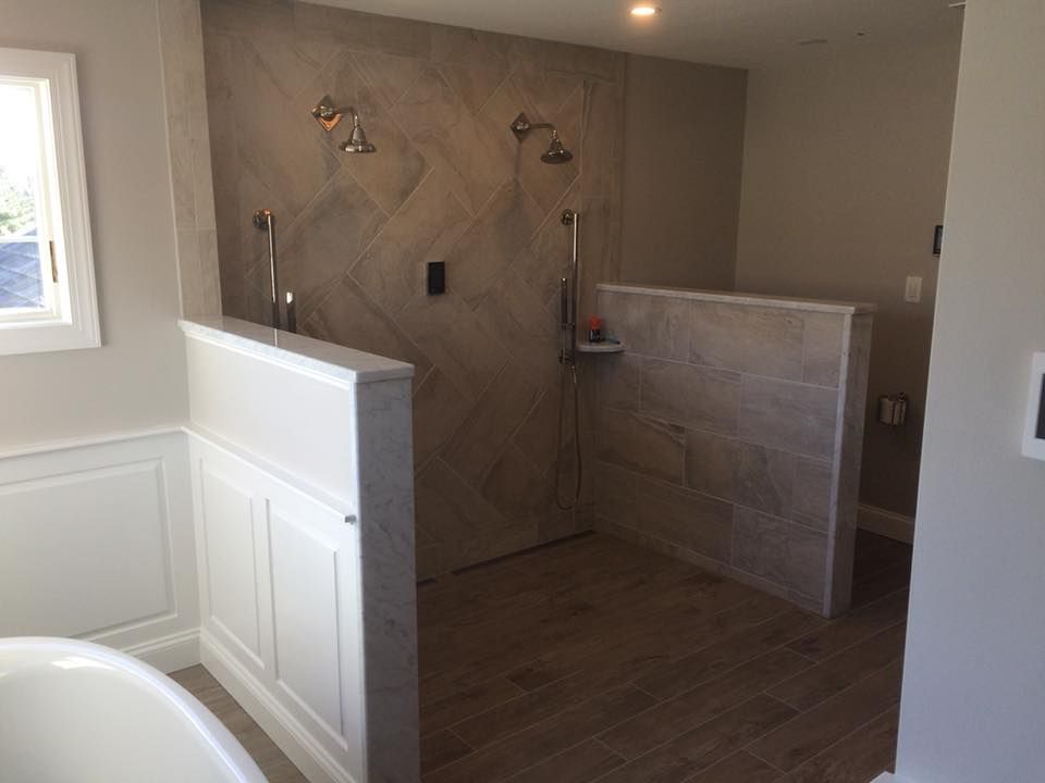 Partially finished bathroom with tiled shower, half wall, and wood-look floor