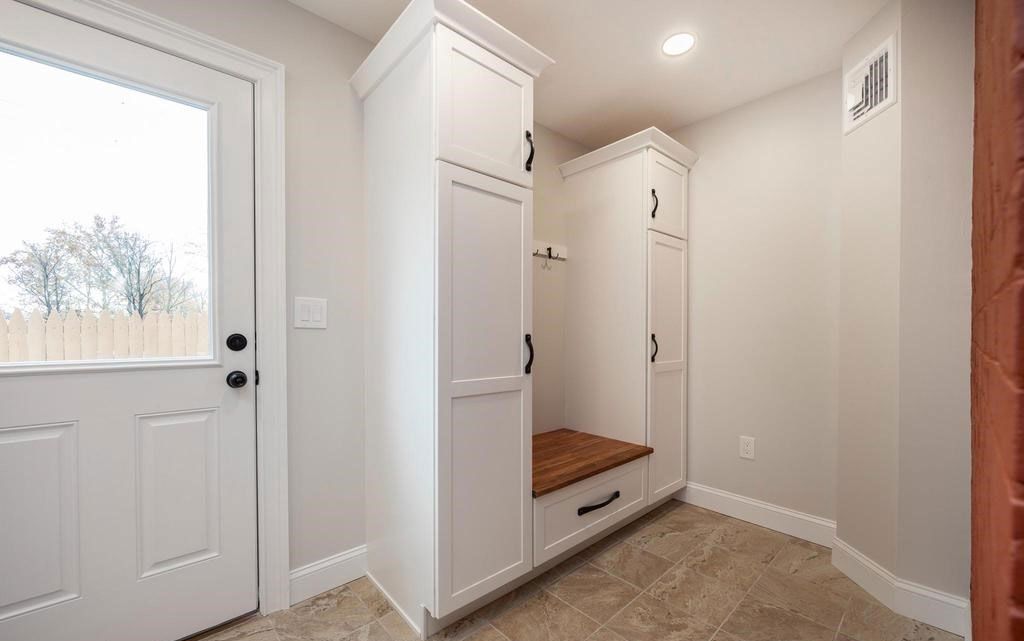 Entryway with white built-in cubbies, a front door, and beige carpet in a bright hallway