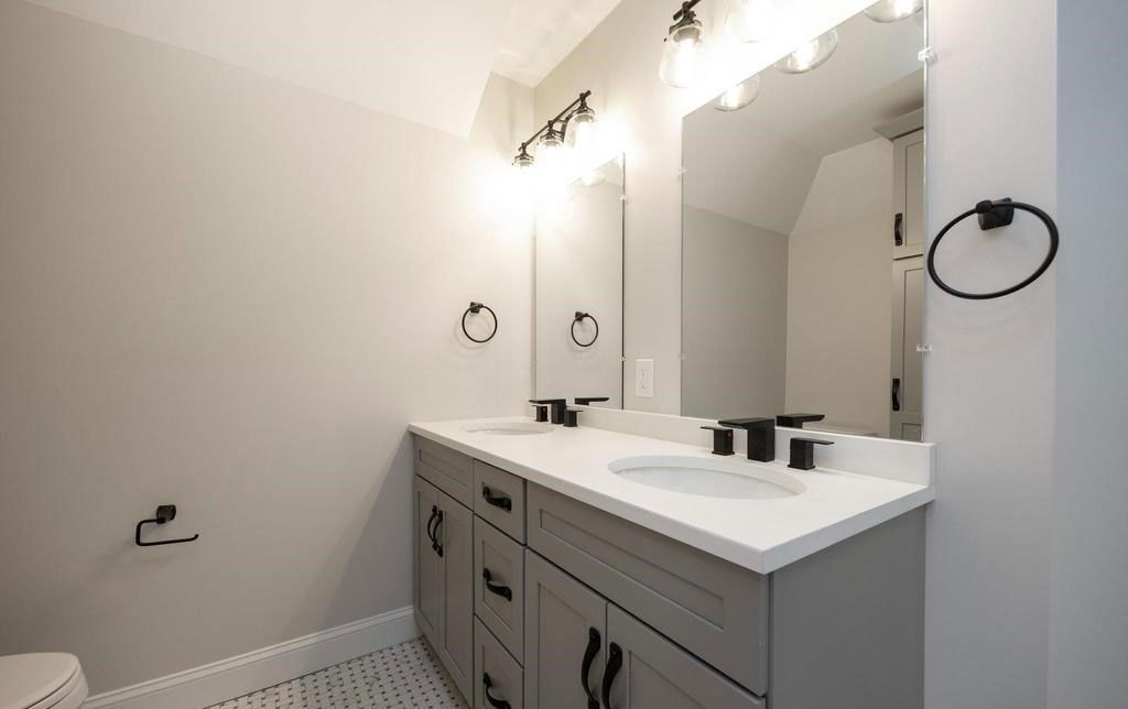 Bright bathroom vanity with double sinks, large mirrors, and wall sconces in a white and gray room
