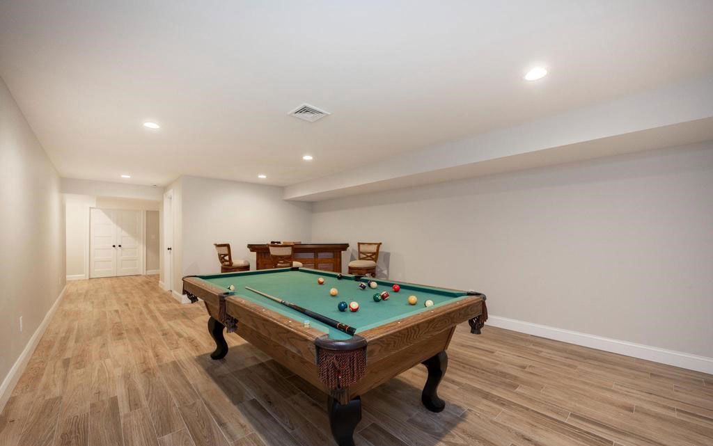 Spacious basement game room with a pool table, wood floors, and recessed lighting