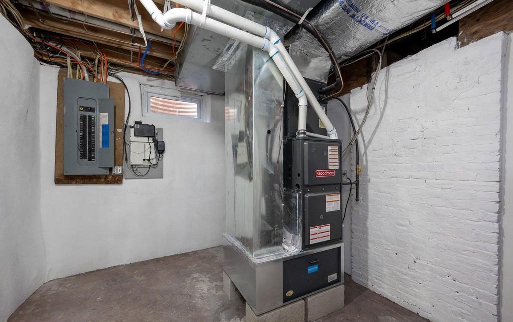 Basement utility room with a furnace, metal ductwork, and electrical panels.