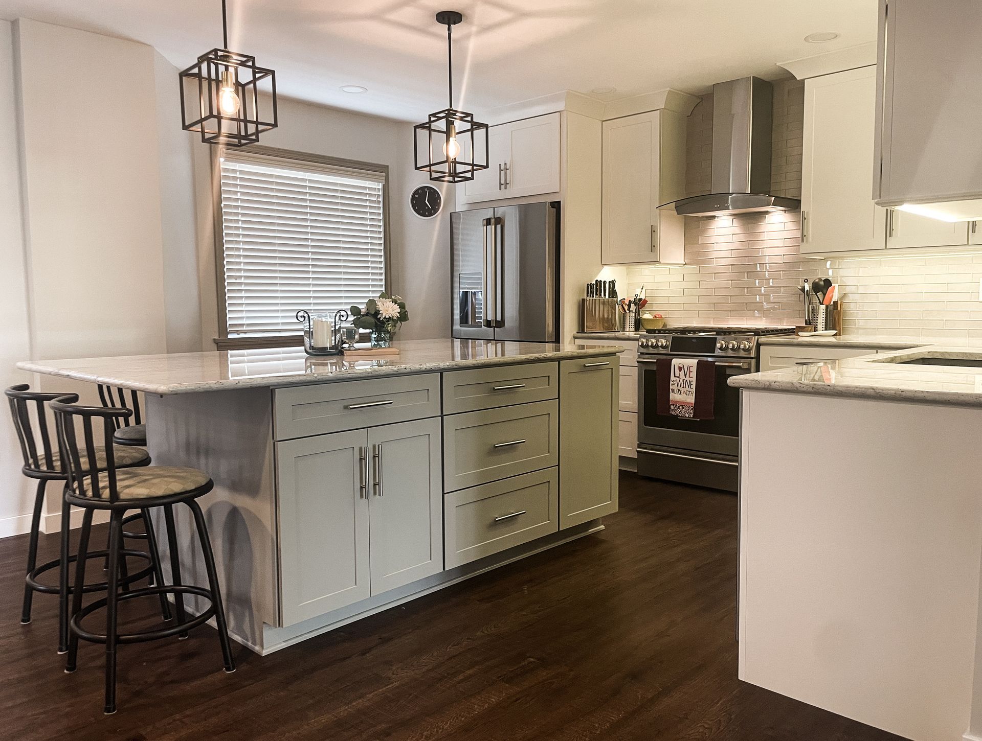 Modern kitchen with island, gray cabinets, pendant lights, and stainless steel appliances