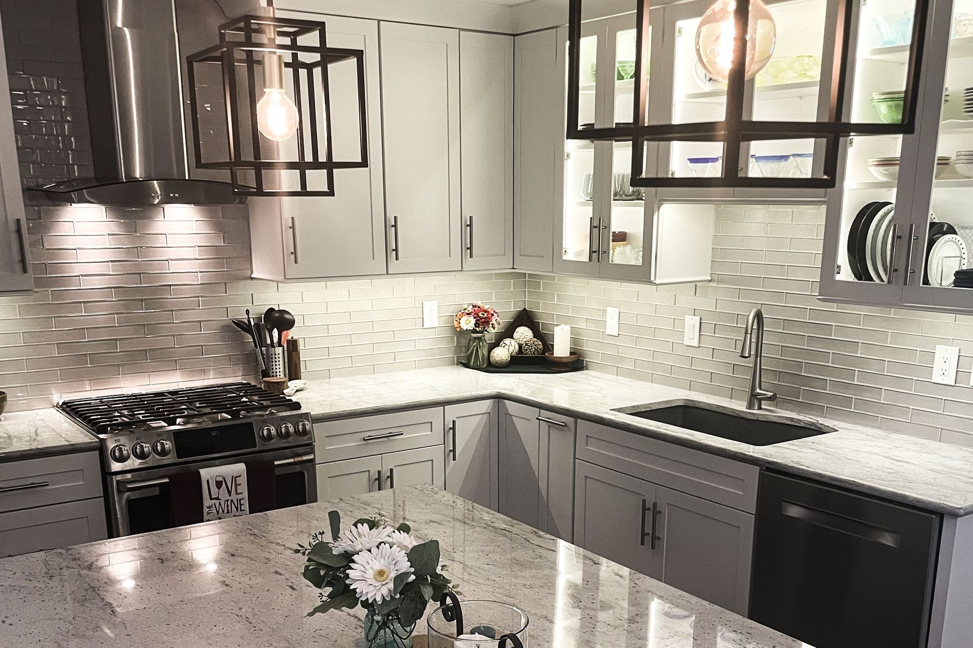 Modern gray-and-white kitchen with stainless steel appliances, marble countertops, and pendant lights