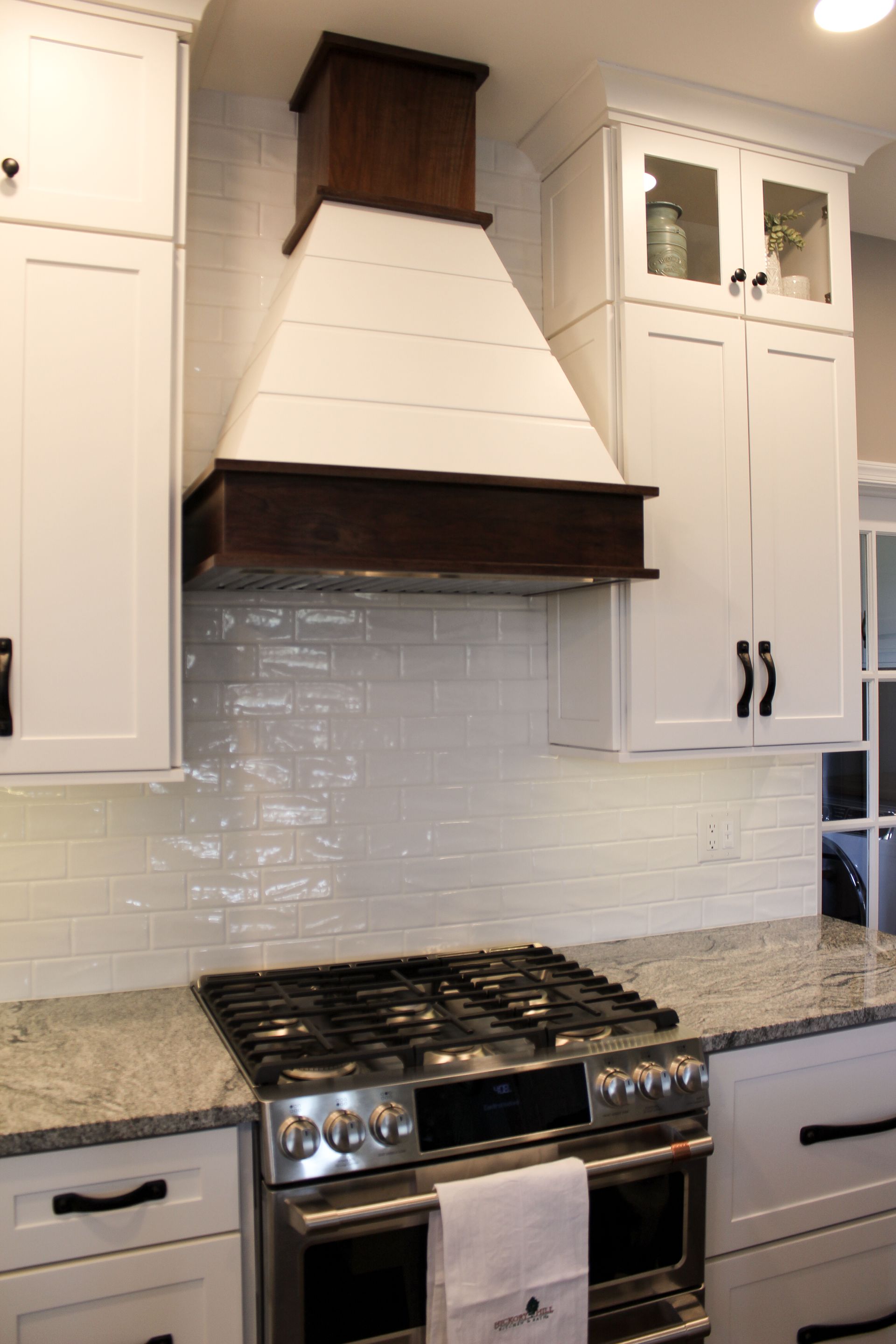 Modern kitchen with white cabinets, granite counters, gas range, and white tile backsplash