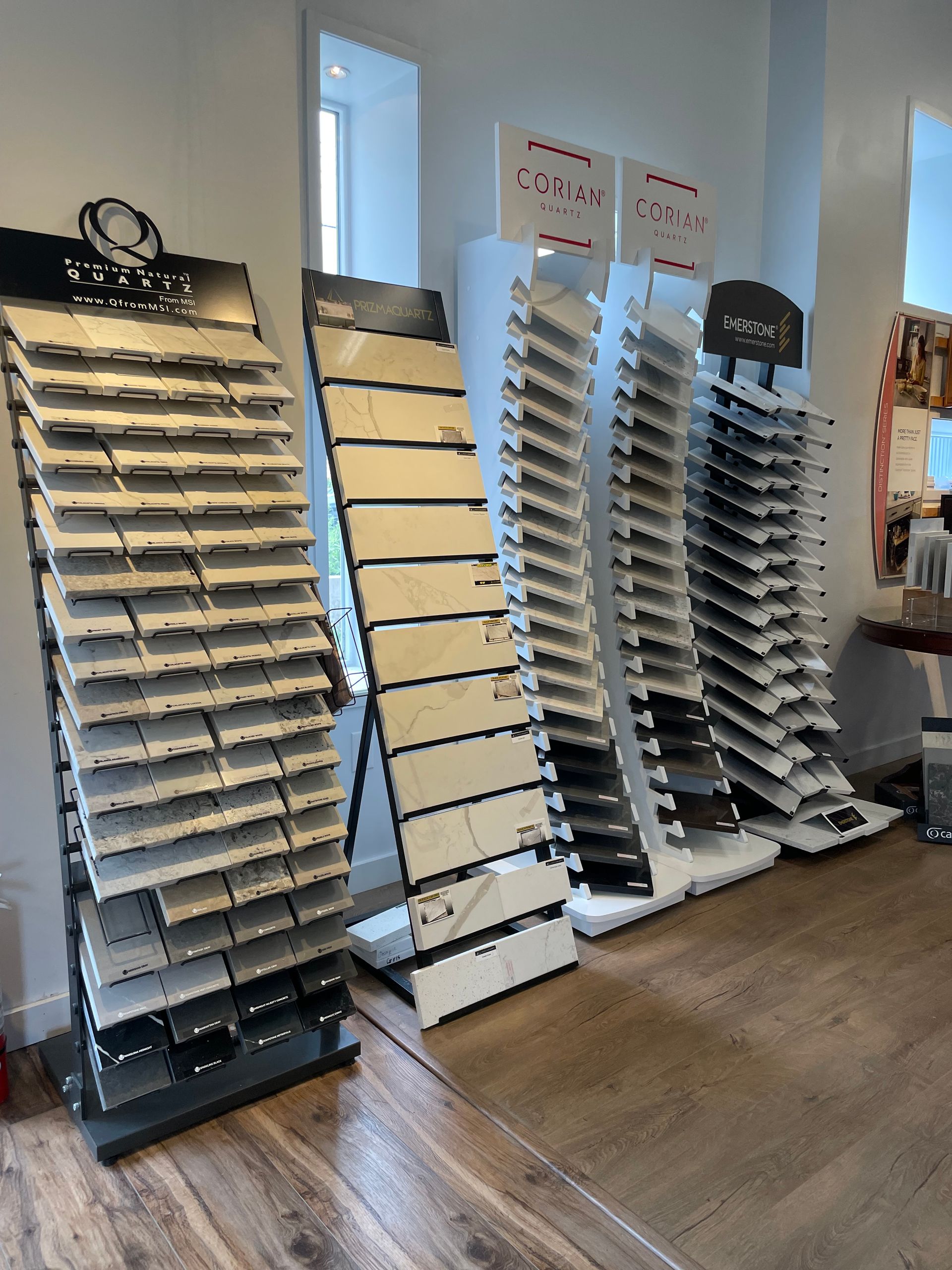 Rows of eyeglass display racks in a bright store showroom with wood flooring