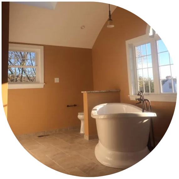 Empty bathroom with tan walls, tiled floor, tub, toilet, windows, and a hanging light fixture.