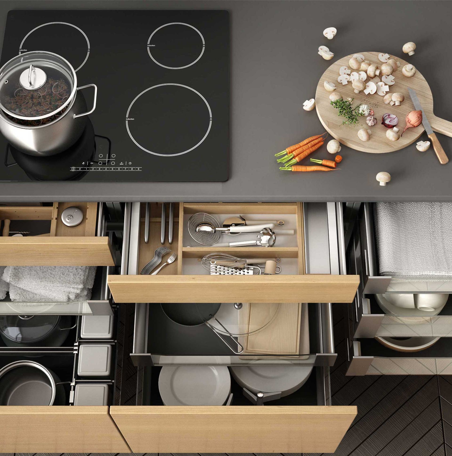 Modern kitchen countertop with stovetop, bowl of flowers, and open drawer organizers with dishes and utensils