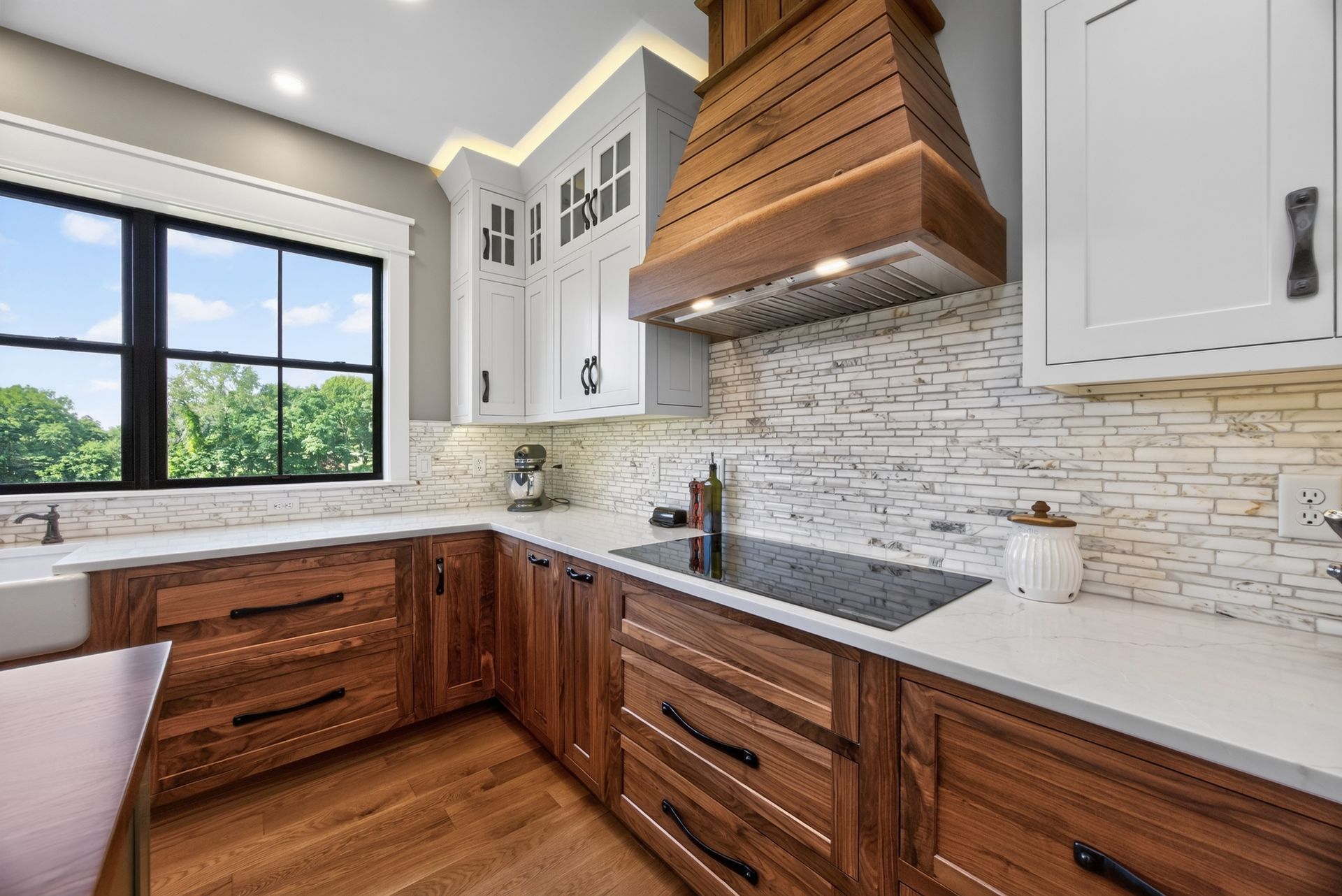 Bright modern kitchen with wood cabinets, white counters, a tile backsplash, and a large window.