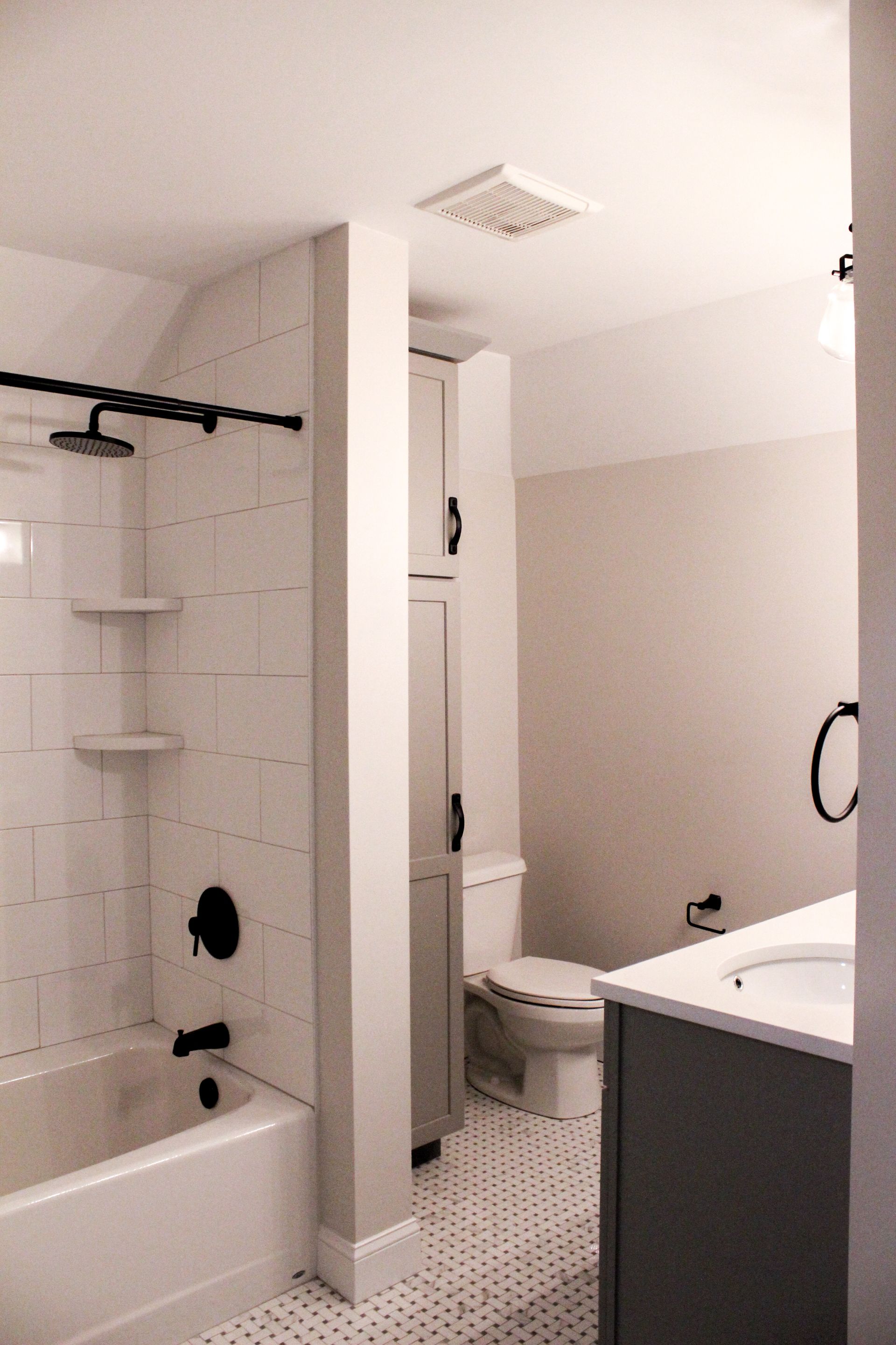 Small modern bathroom with a tub-shower, toilet, and vanity in neutral tones.