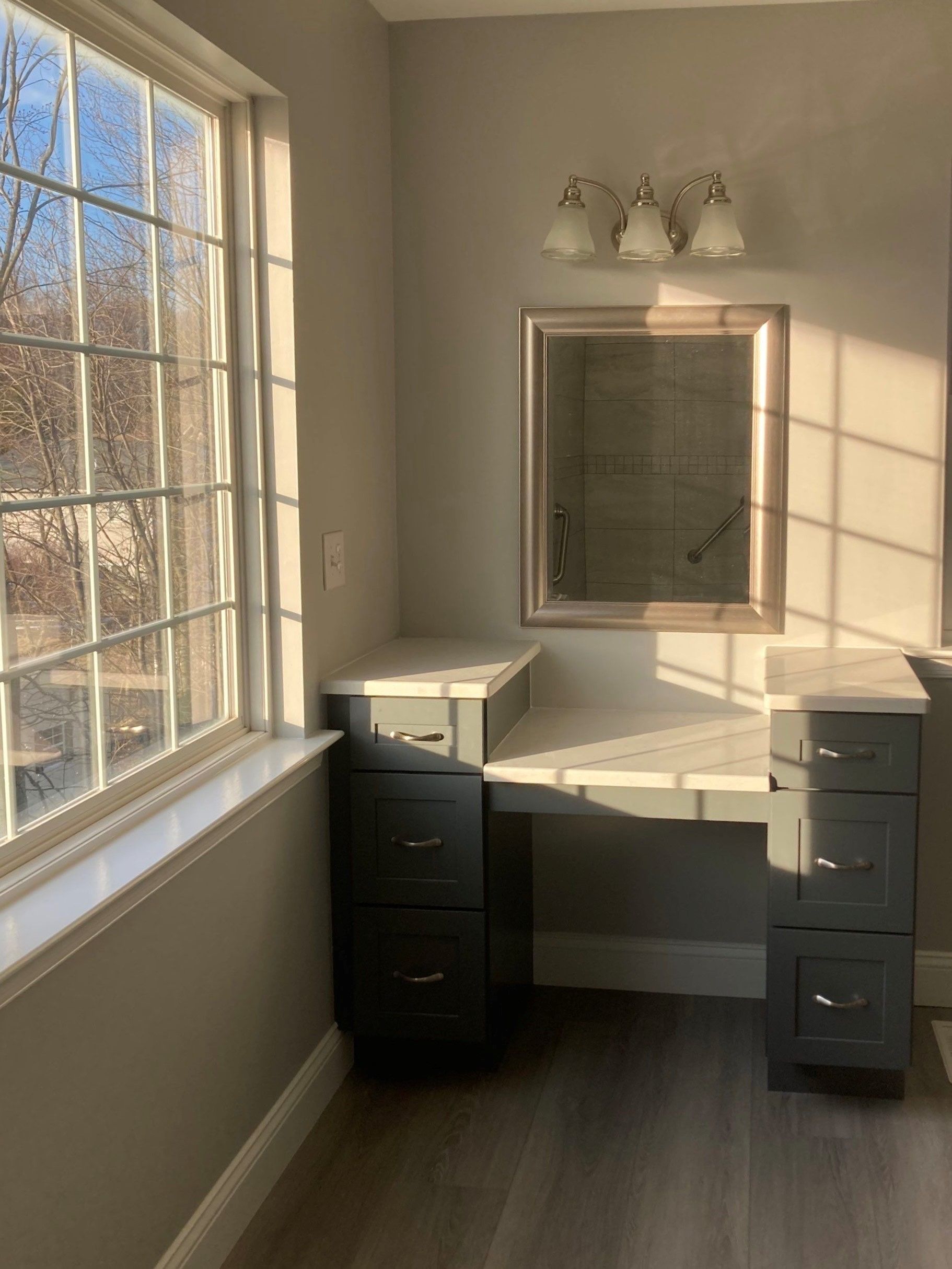 Sunlit vanity table with mirror, drawers, and a window in a beige room