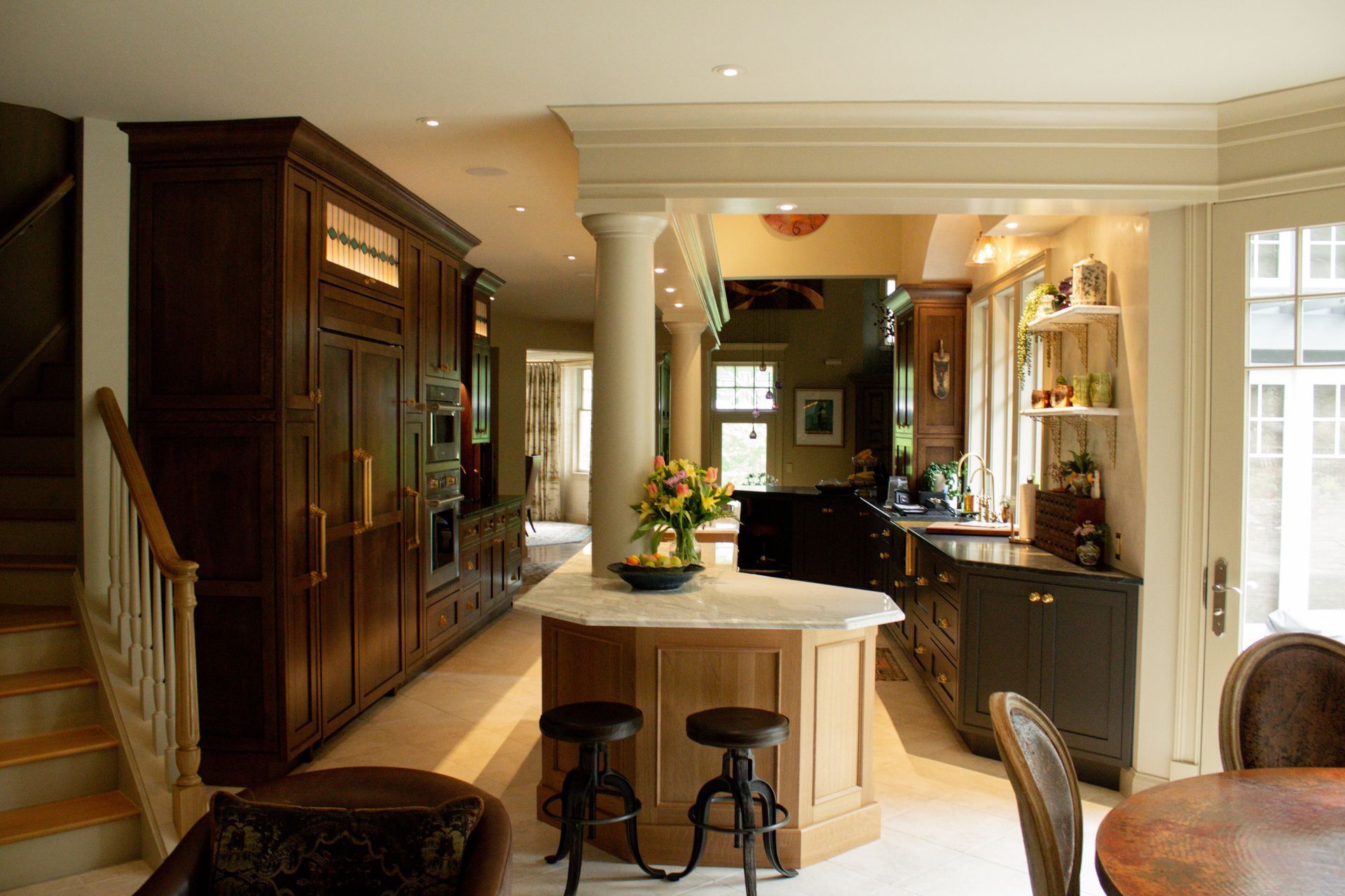 Elegant kitchen with island, bar stools, dark wood cabinets, and warm lighting