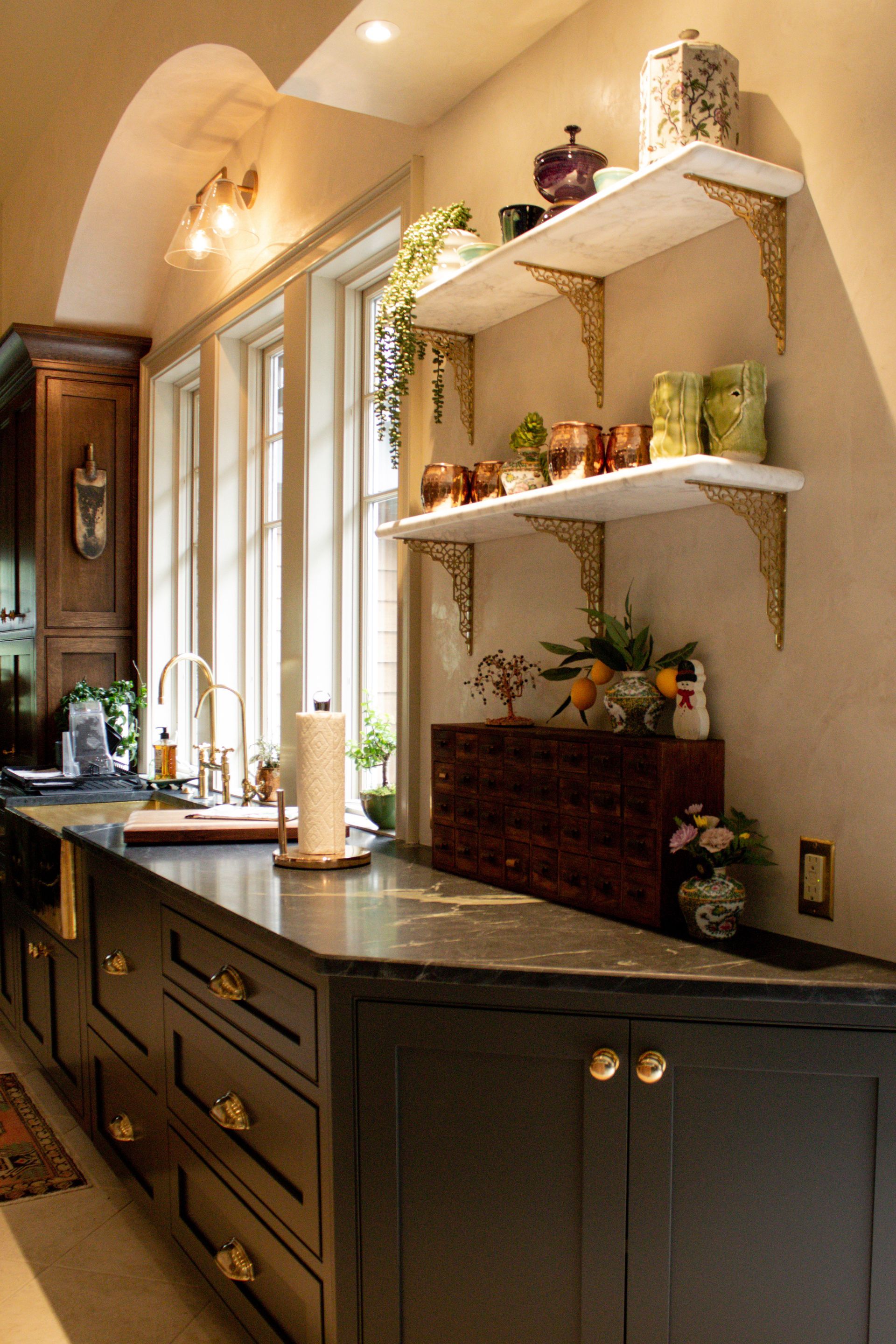 Elegant kitchen sideboard with dark cabinets, granite countertop, and decorative shelves against a warm beige wall