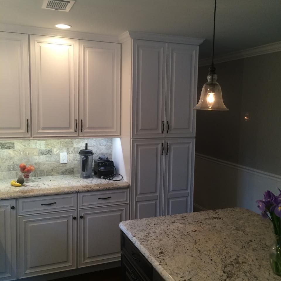 Modern kitchen with white cabinets, under-cabinet lighting, granite island, and hanging pendant light