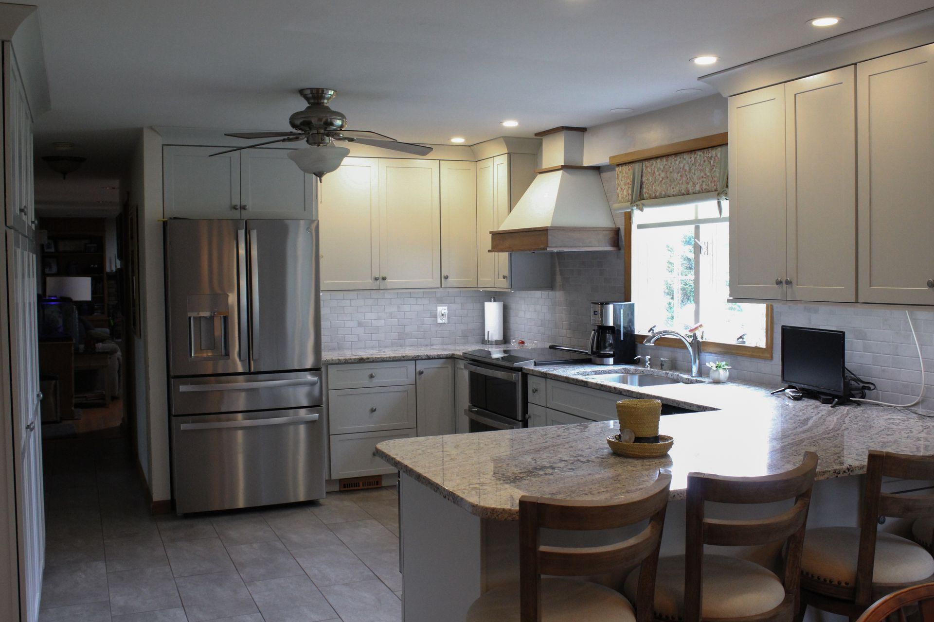 Modern kitchen with stainless steel appliances, cream cabinets, granite island, and a window over the sink