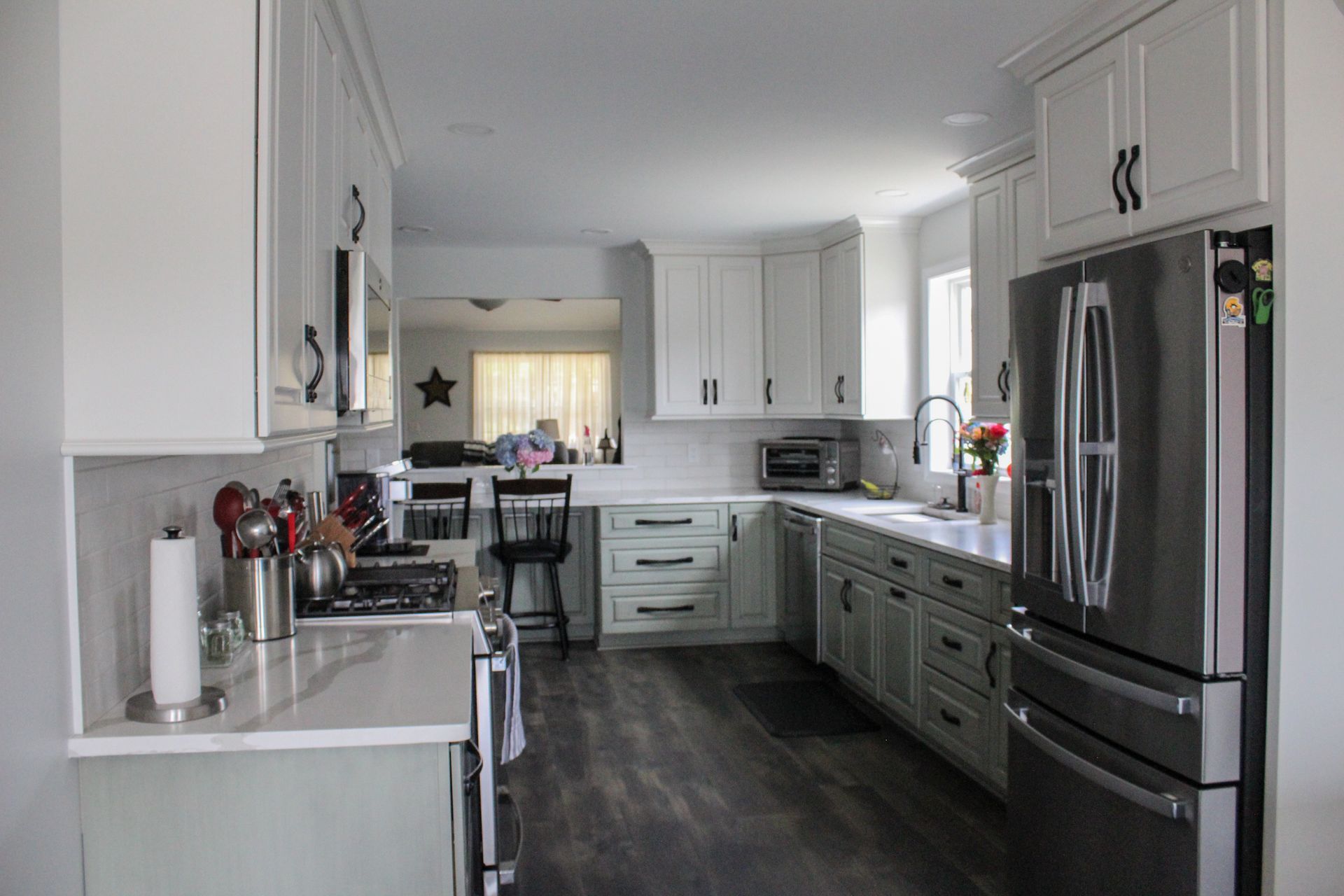 Bright modern kitchen with white cabinets, stainless steel appliances, and dark wood flooring
