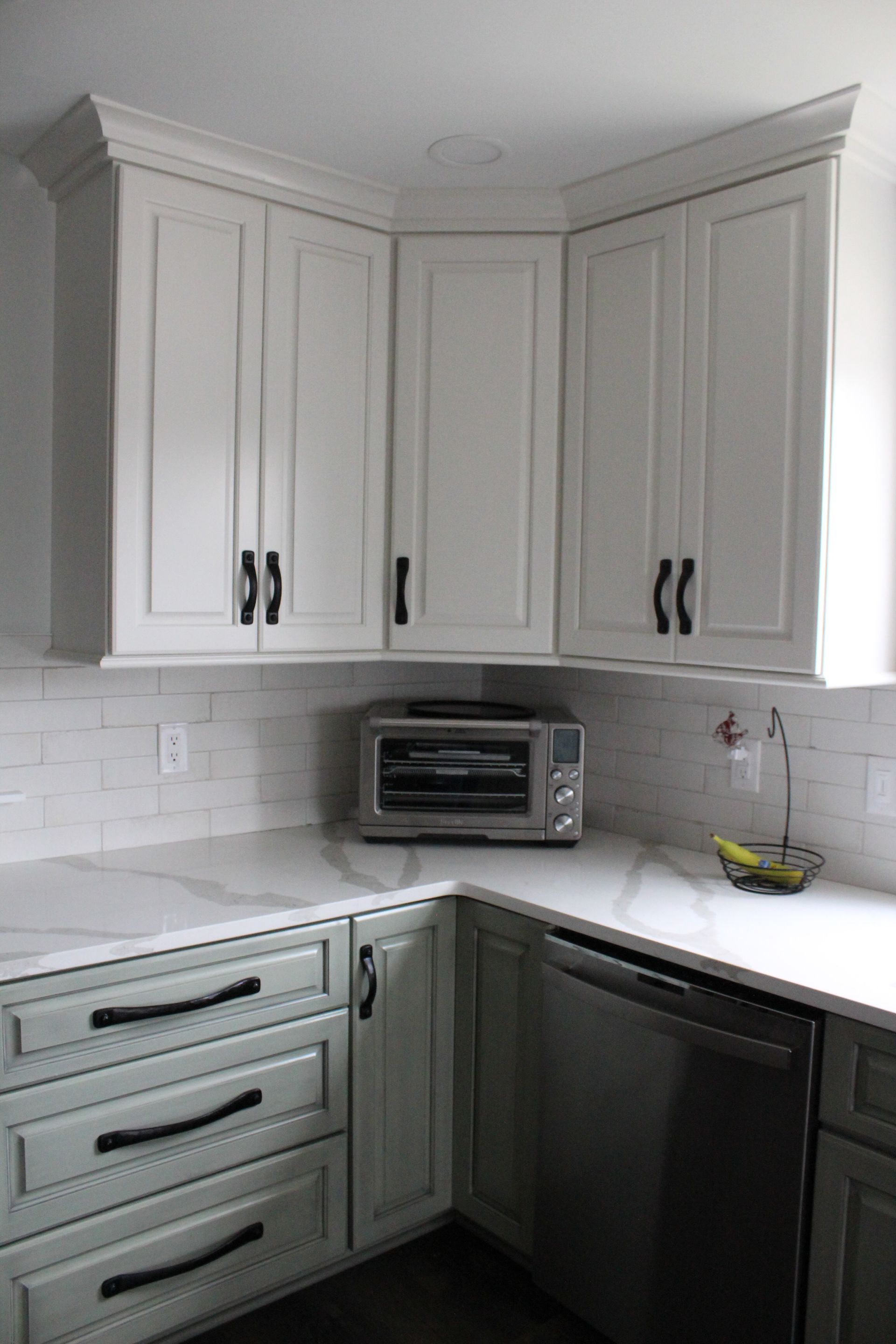 White kitchen corner with cabinets, granite countertop, microwave, dishwasher, and sink area