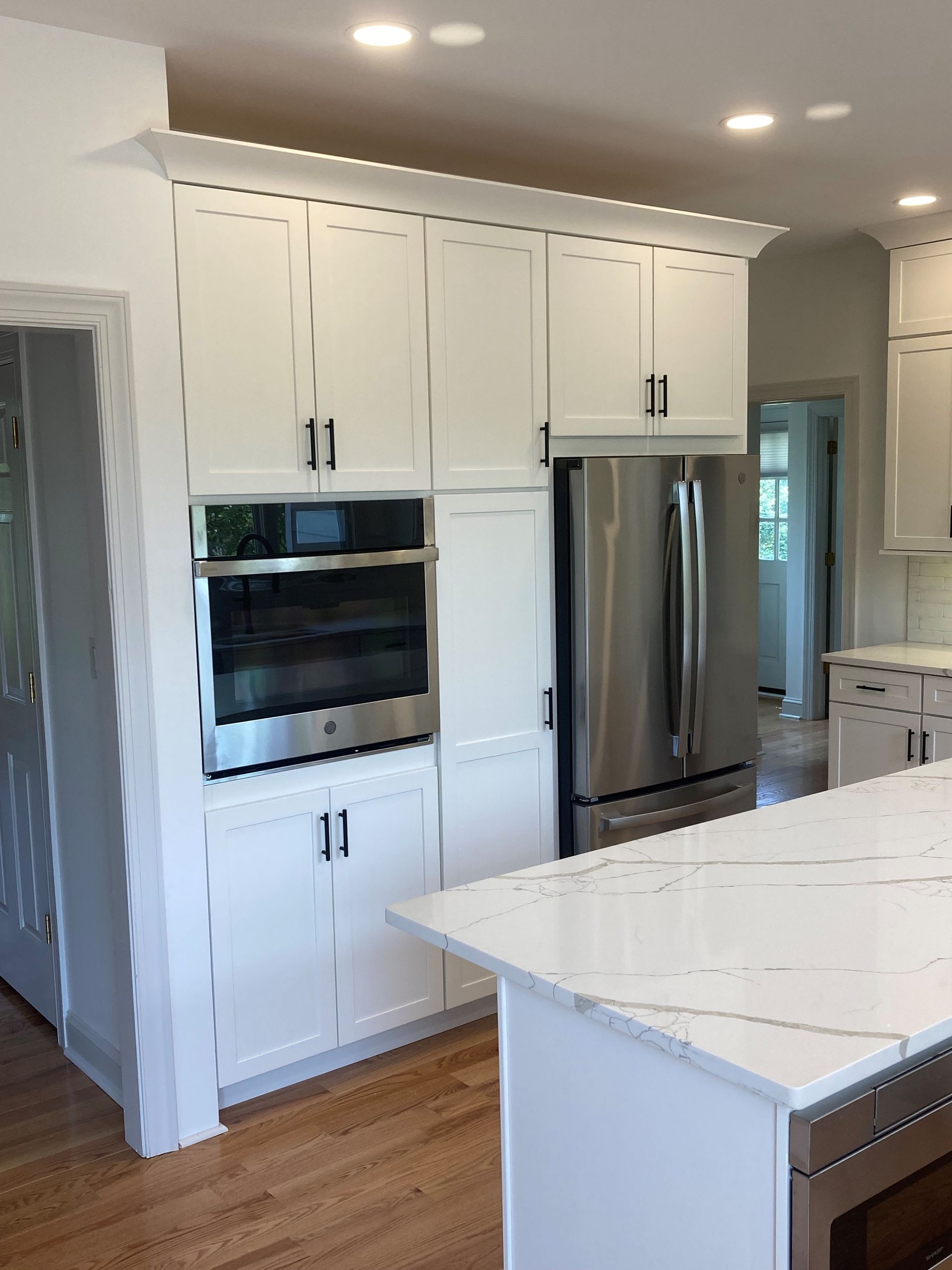 Modern white kitchen with stainless steel appliances, island, and wood flooring