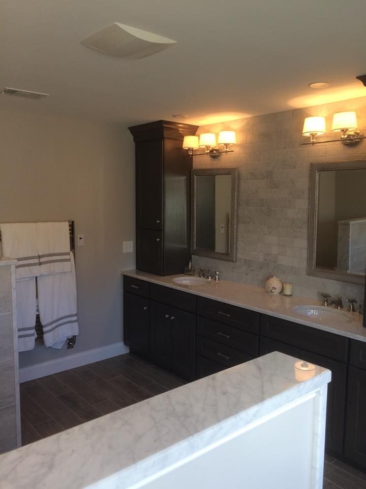 Empty bathroom with double vanity, large mirror, and warm wall sconces.
