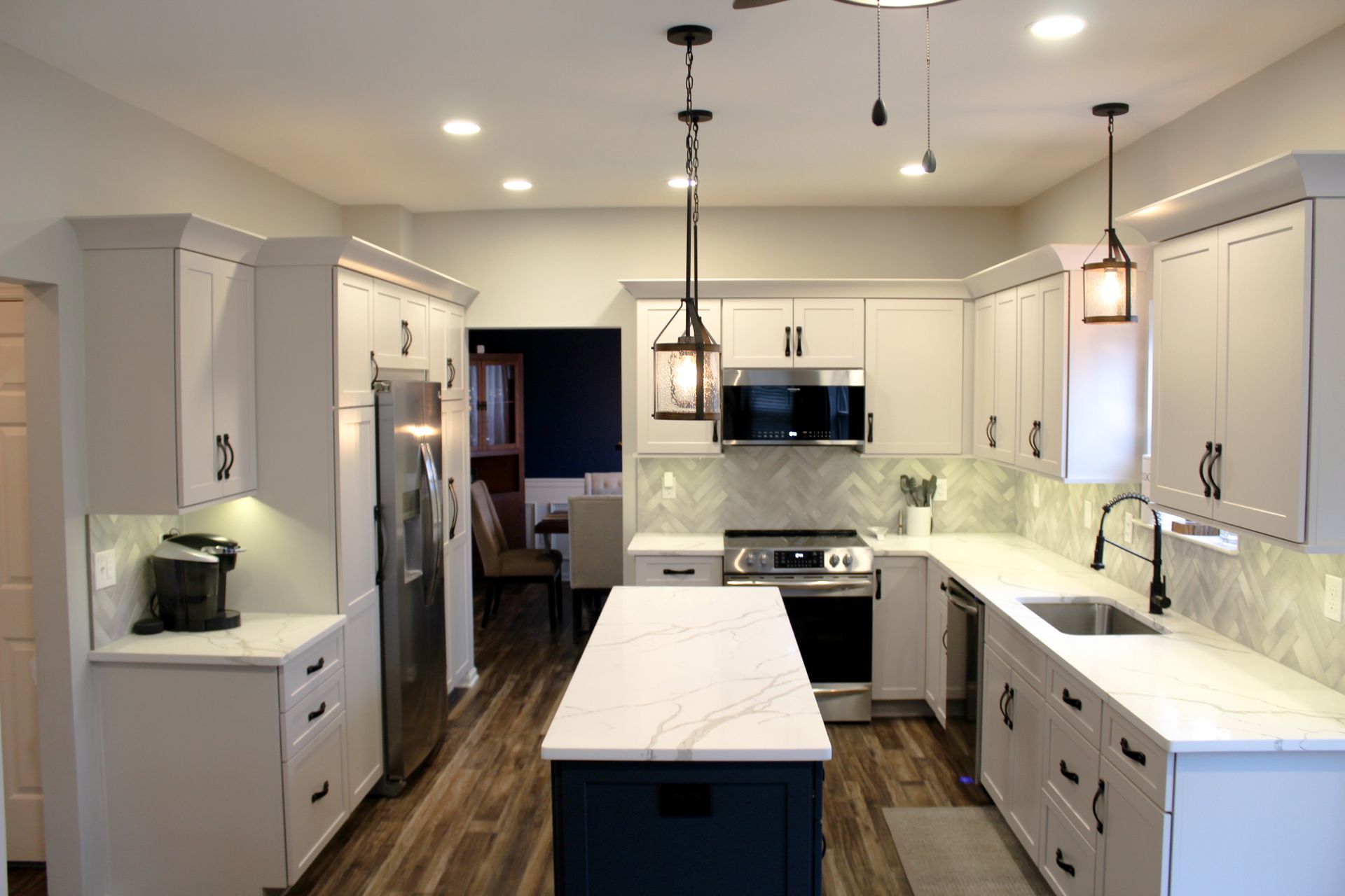Modern white kitchen with island, pendant lights, and dark wood flooring