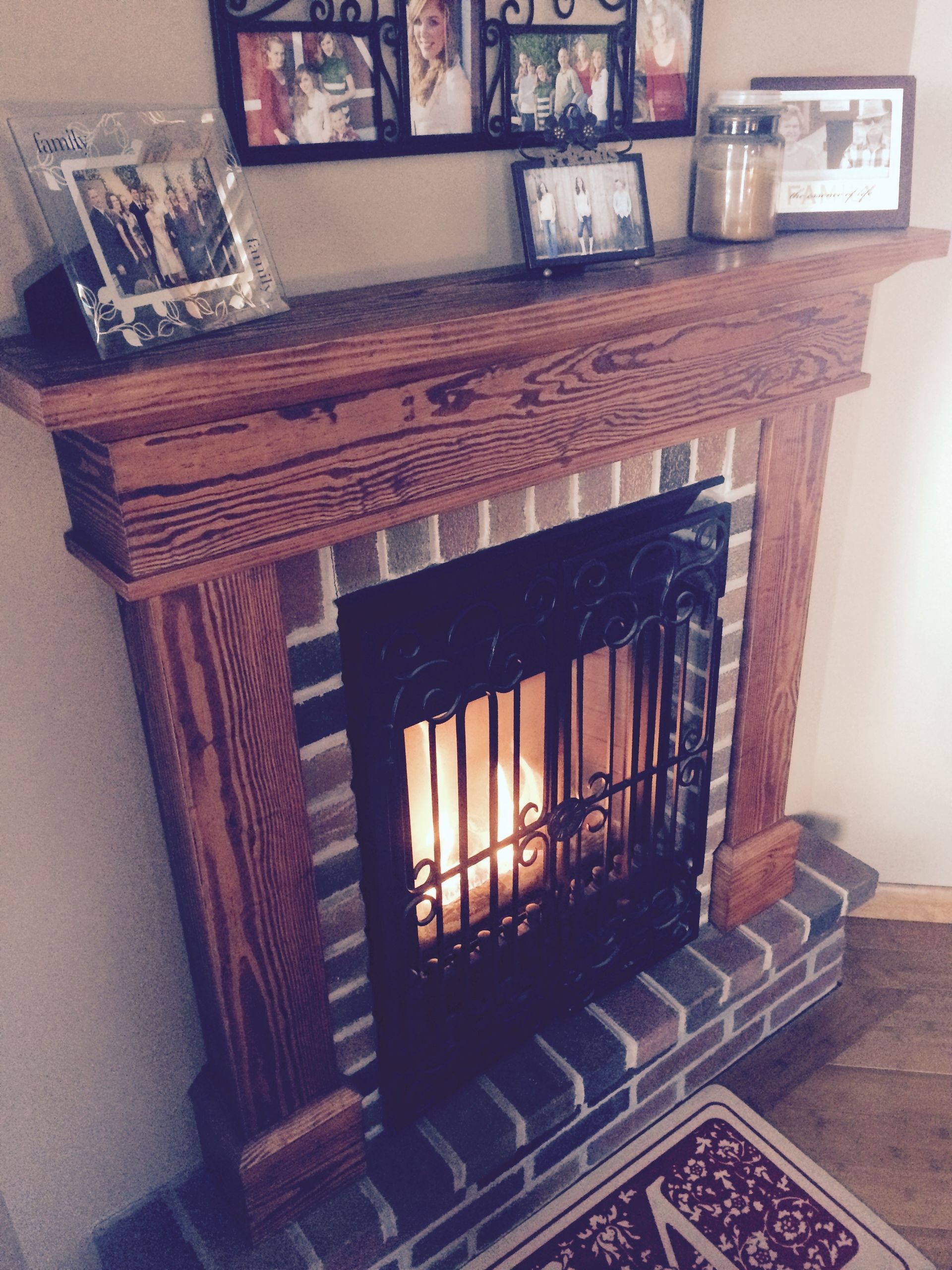 Lit fireplace with ornate wooden mantel and framed photos above it