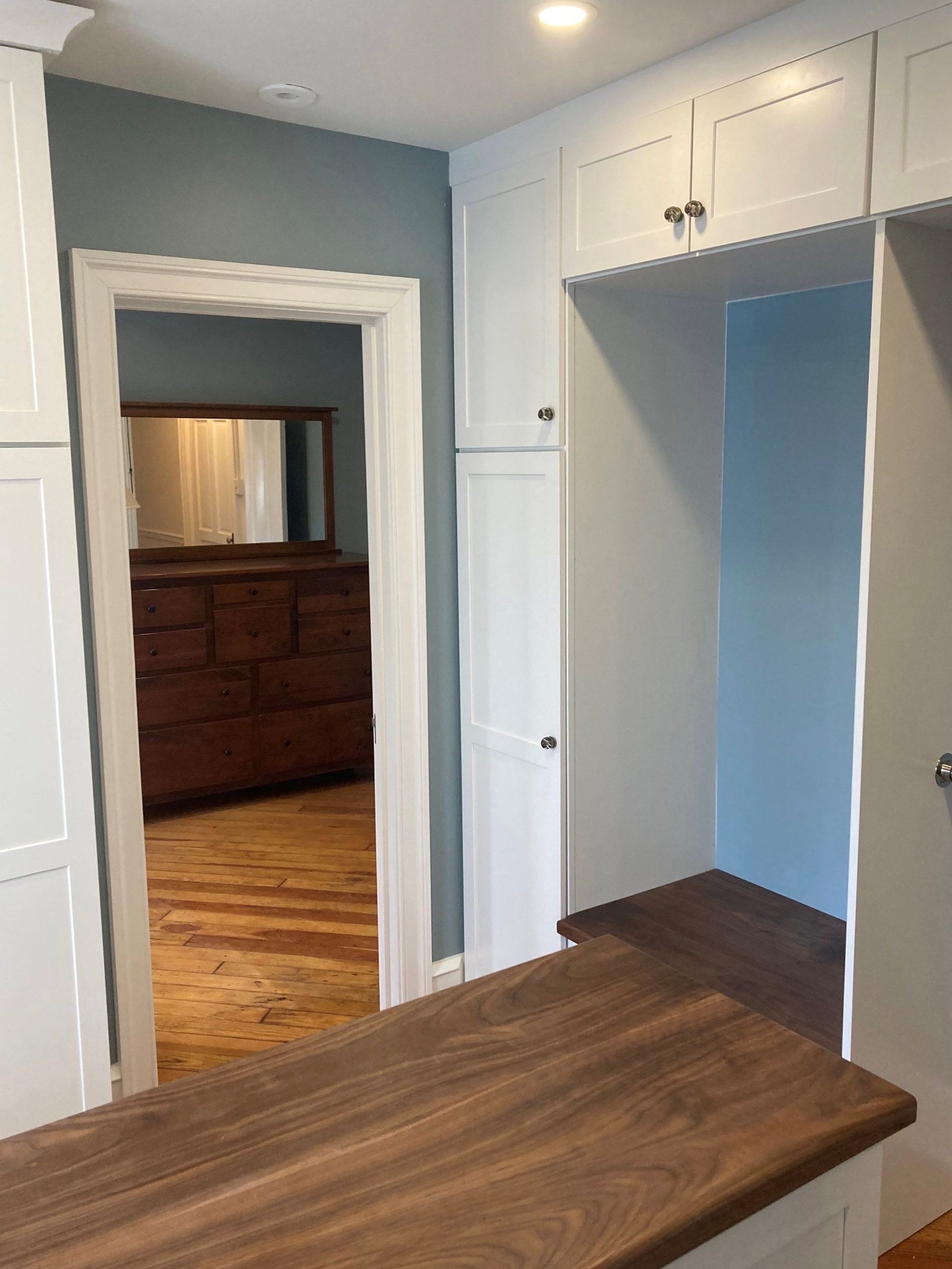 Built-in white cabinets and a dark wood countertop in a small hallway nook