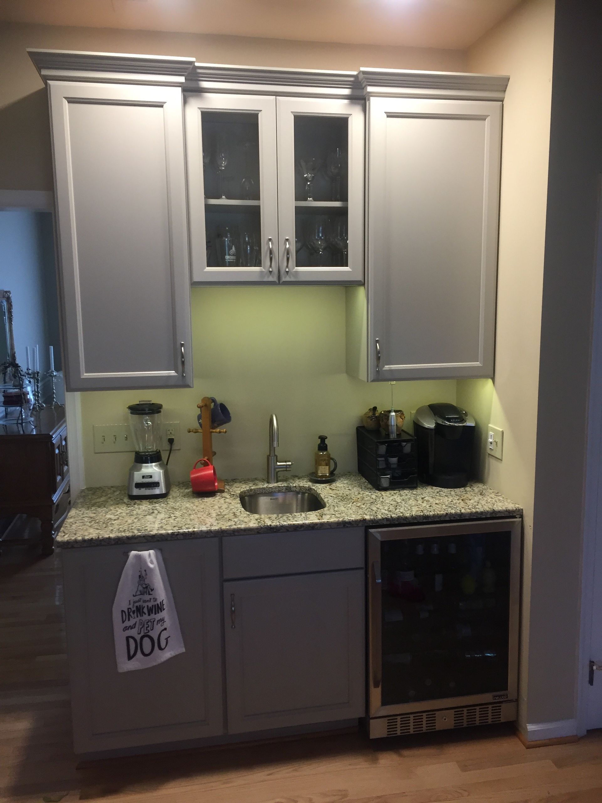 Kitchen kitchenette with gray cabinets, granite counter, sink, small appliances, and under-cabinet green lighting.