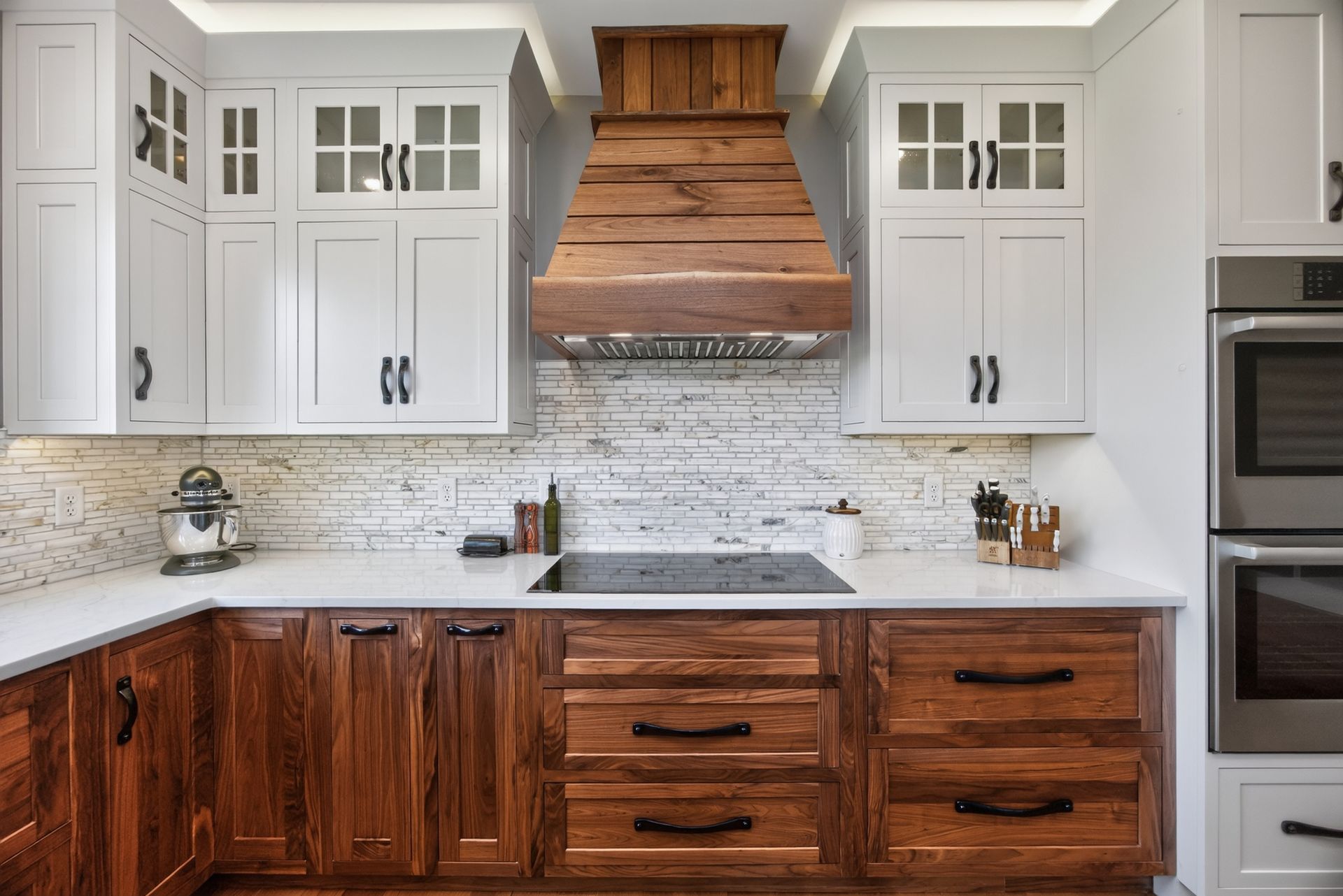 Modern kitchen with white cabinets, dark wood lower cabinets, marble backsplash, and copper range hood